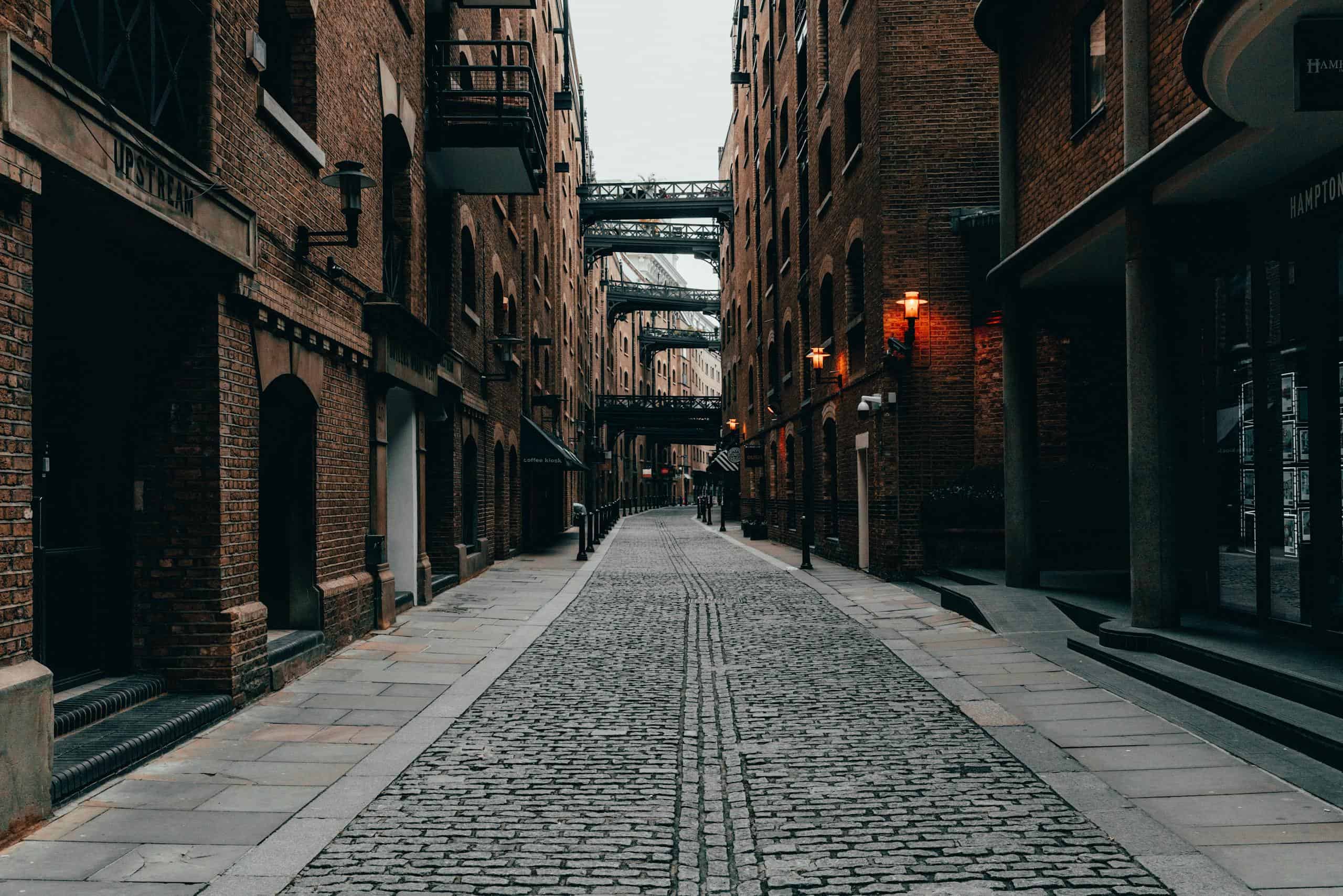 Cobblestone alleyway in London's atmospheric downtown, enclosed by brick buildings.